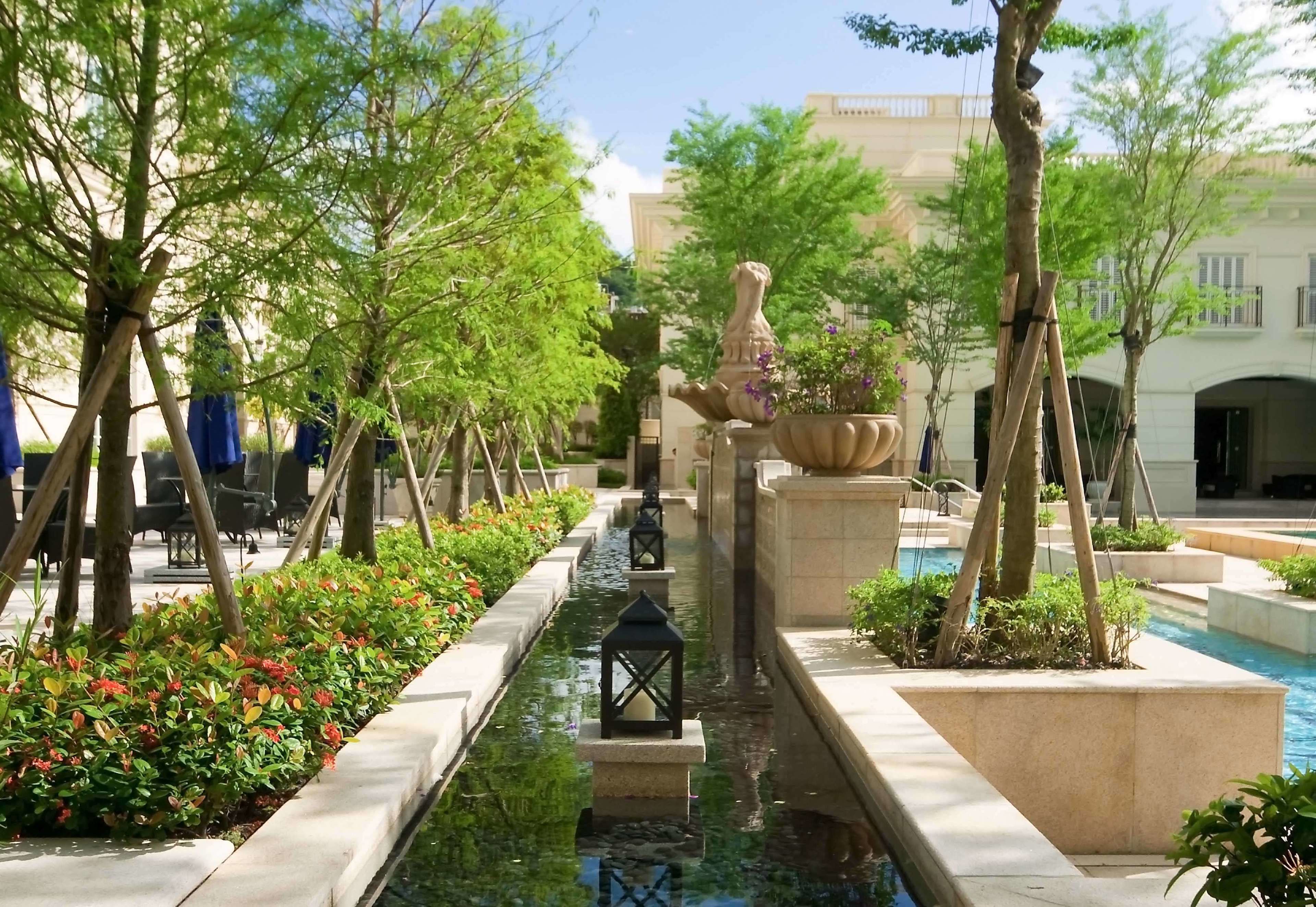 A serene courtyard with a water feature, stone lanterns, and lush greenery.