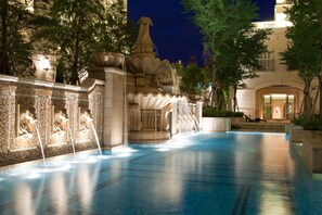 A nighttime pool area with a central fountain, surrounded by trees and a building with a balcony. - RSL Cold & Hot Springs Resort Suao (Suao)
