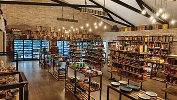 A spacious store with high ceilings, exposed brick walls, and wooden beams. Shelves are stocked with a variety of products, and there are hanging light fixtures.