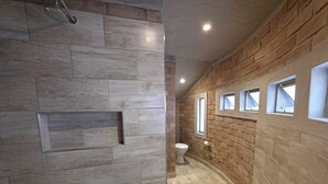 A modern bathroom with a shower, toilet, and a vanity with a mirror. - Sossus Oasis Camp Site (Sesriem)