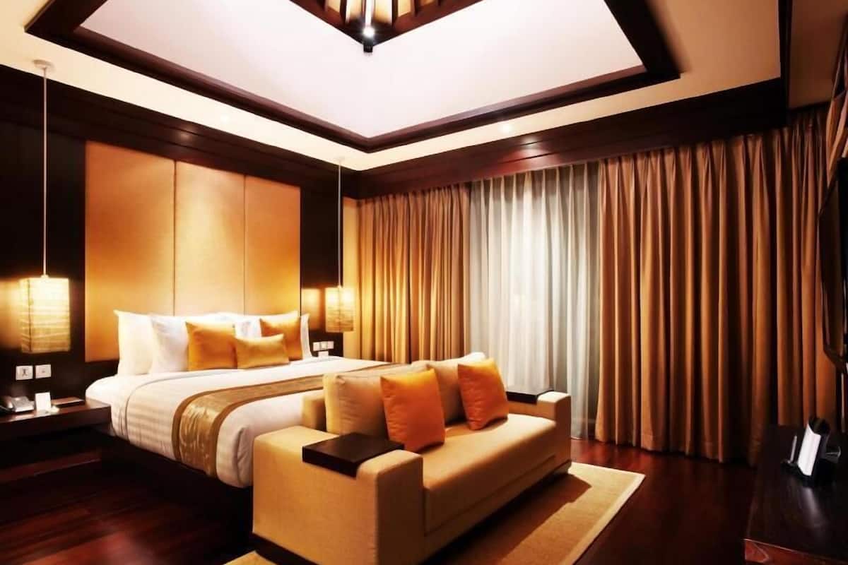 Een moderne hotelkamer met een groot bed, een bank, een bureau en een groot raam met gordijnen.