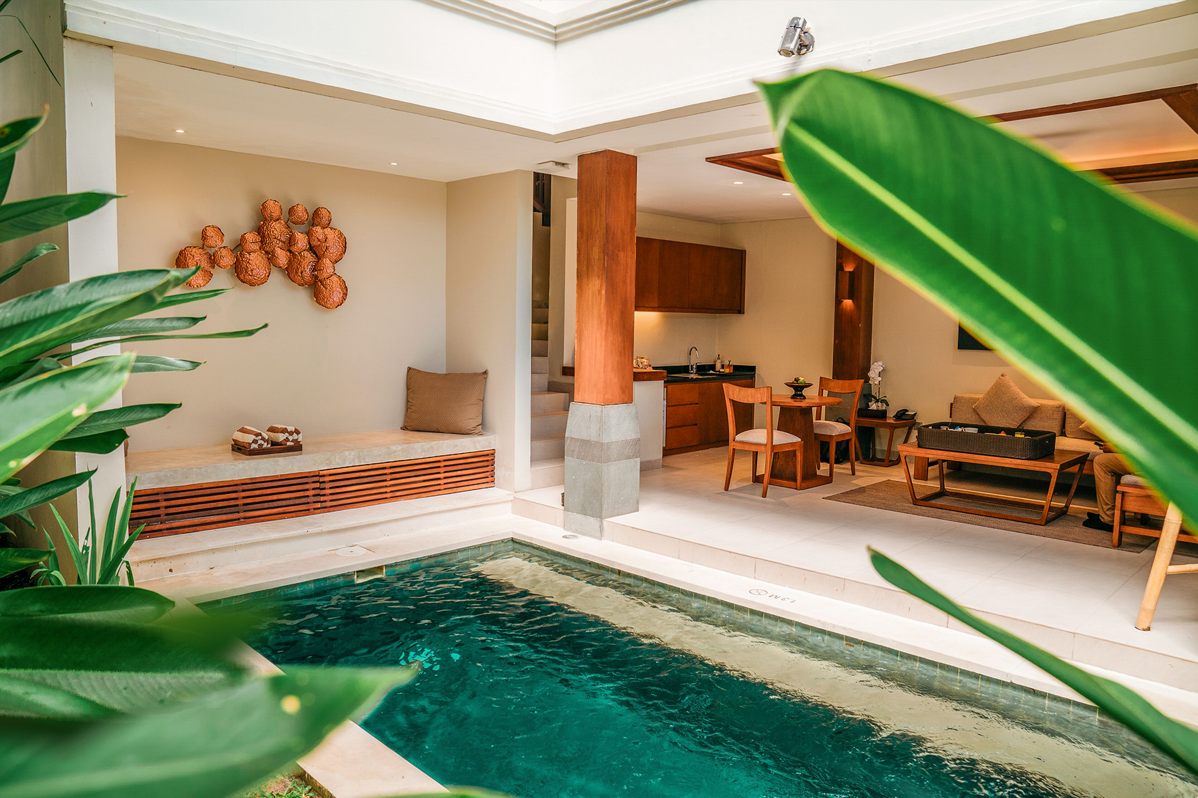A modern interior with a pool, wooden furniture, and a stone column.