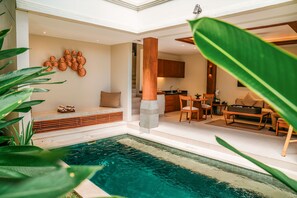 A modern interior with a pool, wooden furniture, and a stone column.