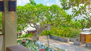 Relax in a serene garden setting with a tranquil water feature, a wooden bench, and a table for a peaceful retreat.
