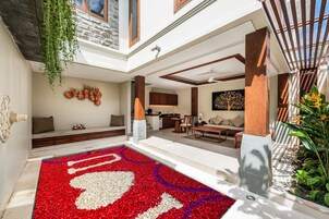 A modern living area with a patterned rug, seating, and a kitchen in the background.