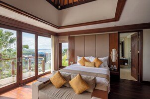 A spacious bedroom with a large bed, a balcony with a view, and a separate bathroom.