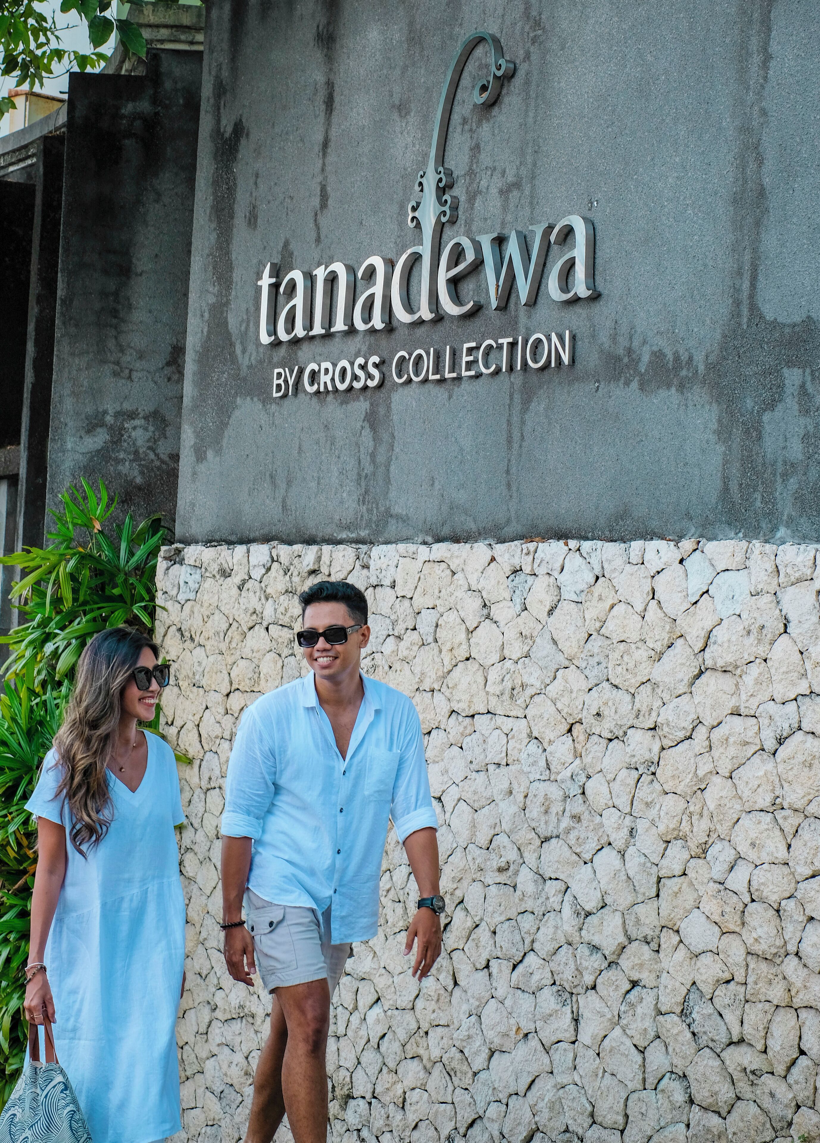 A sign for 'Tanadewa by Cross Collection' against a stone wall.