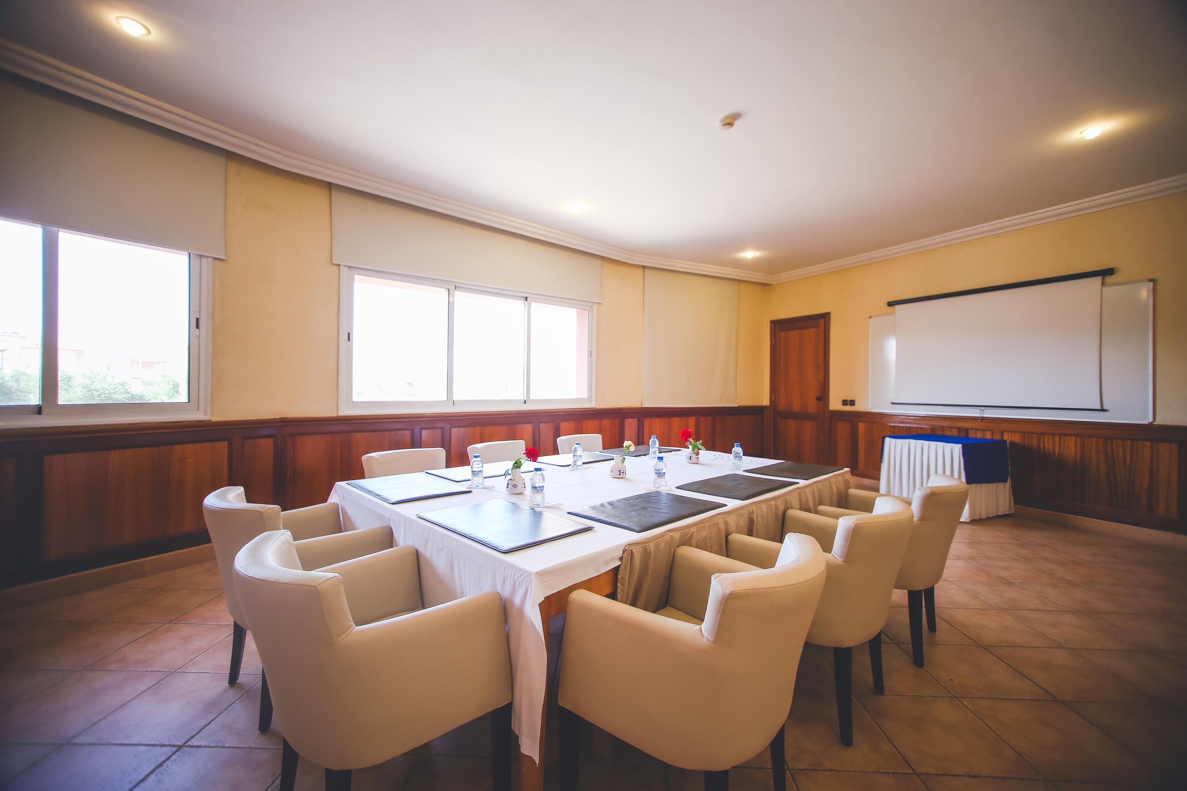 A conference room with a large table, chairs, a whiteboard, and windows.