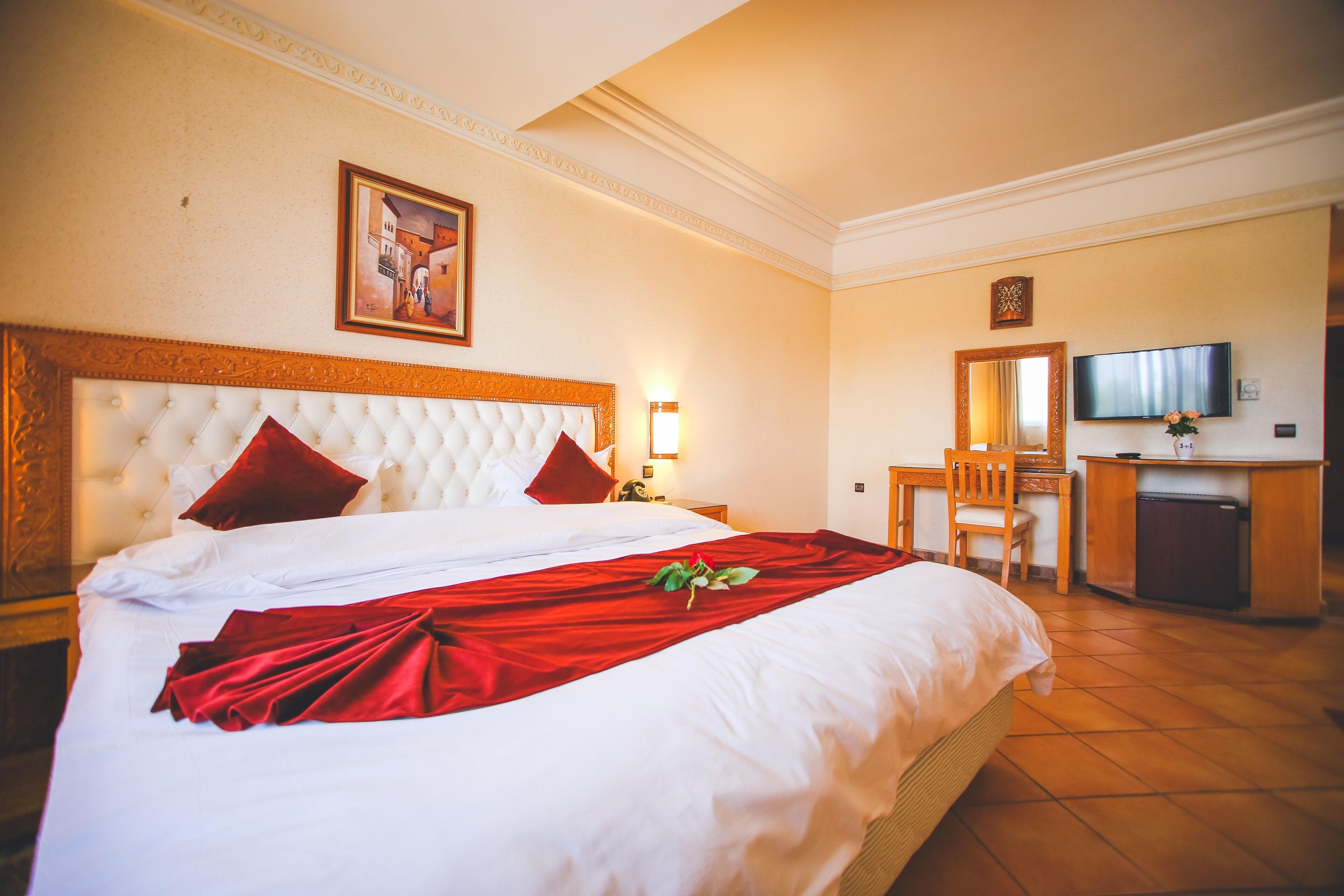 Een hotelkamer met een groot bed, een bureau, een televisietoestel en een spiegel.