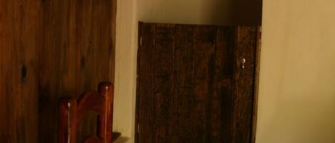 A wooden chair in a room with a thatched ceiling and a wooden door.
