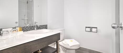 A modern bathroom with a double sink vanity, a toilet, and a shower area.