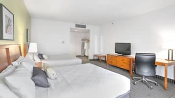 A hotel room with two beds, a desk, a chair, a television, and a wardrobe.