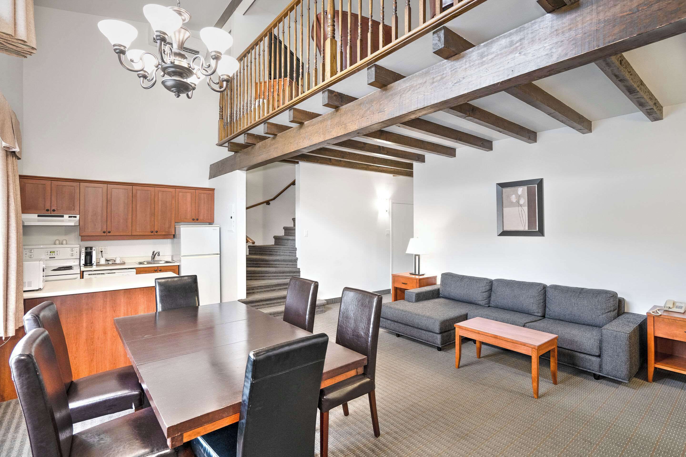 Een ruime woonkamer met een eettafel, bank en trap.