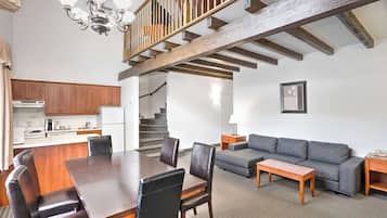 Een ruime woonkamer met een eettafel, bank en trap.
