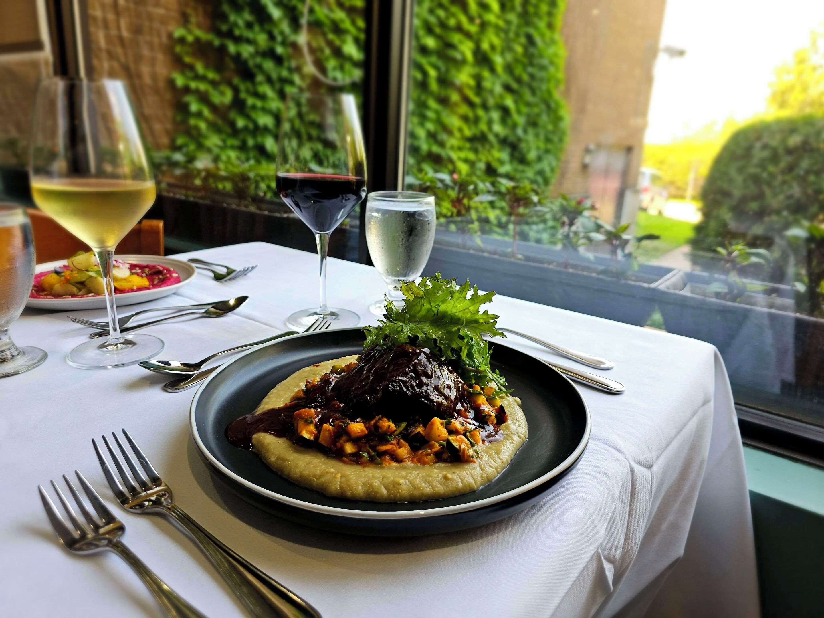 Une table avec une assiette de nourriture, des verres à vin et des couverts.
