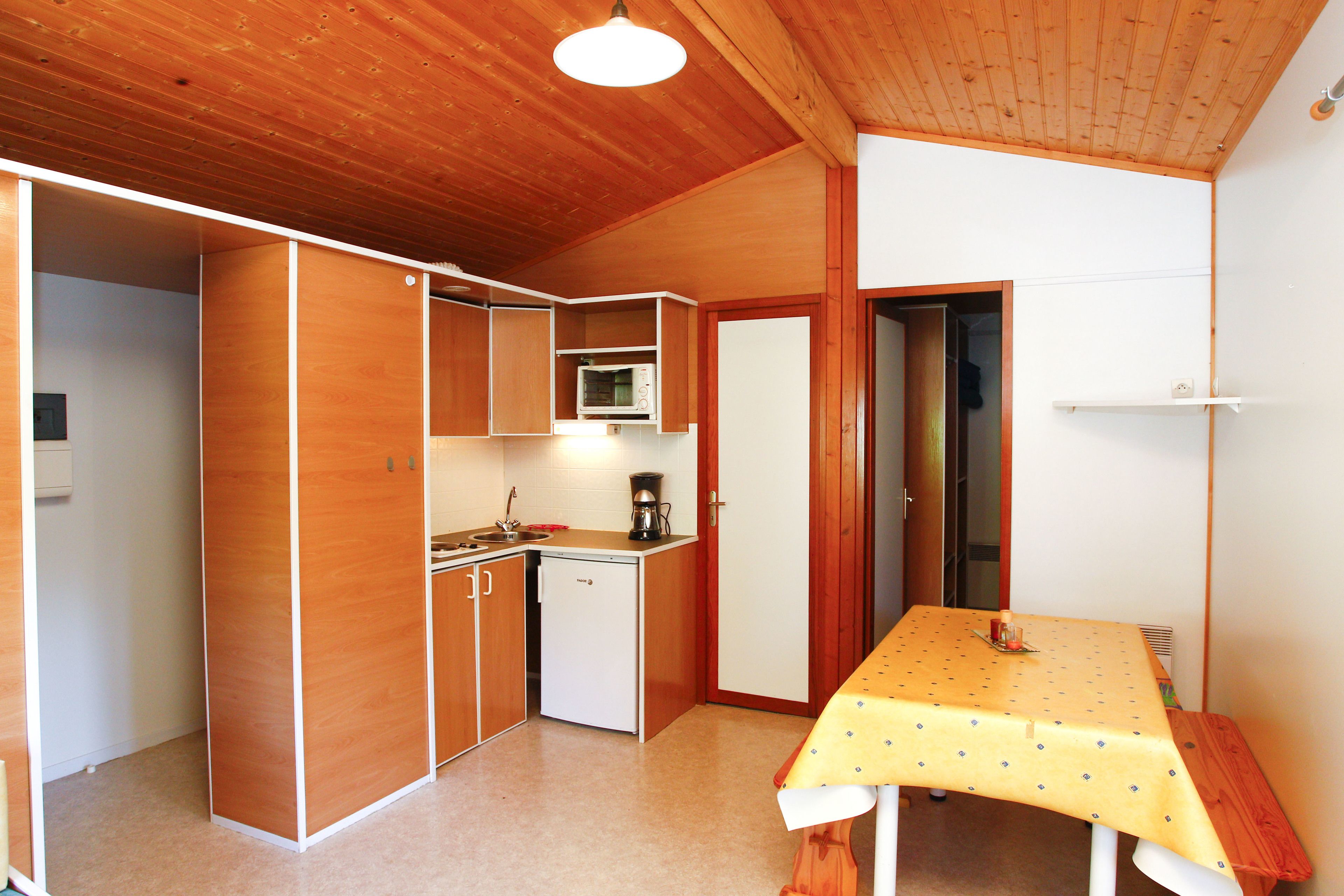 A compact kitchen with wooden cabinets, a microwave, and a small sink.