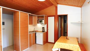 A compact kitchen with wooden cabinets, a microwave, and a small sink.