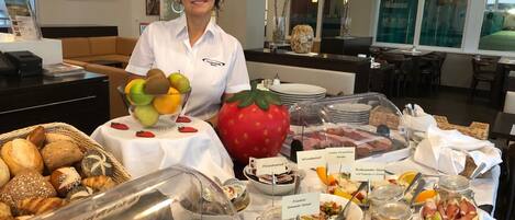 A buffet setup with various food items and a person standing behind it.