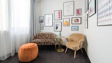 A modern living room with a sofa, armchair, ottoman, and a coffee table.