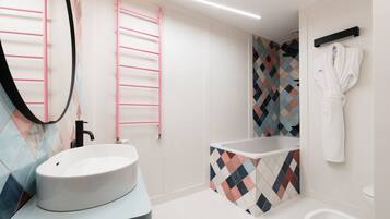 A modern bathroom with a white sink, a freestanding bathtub, and a mirror with a pink towel rack.