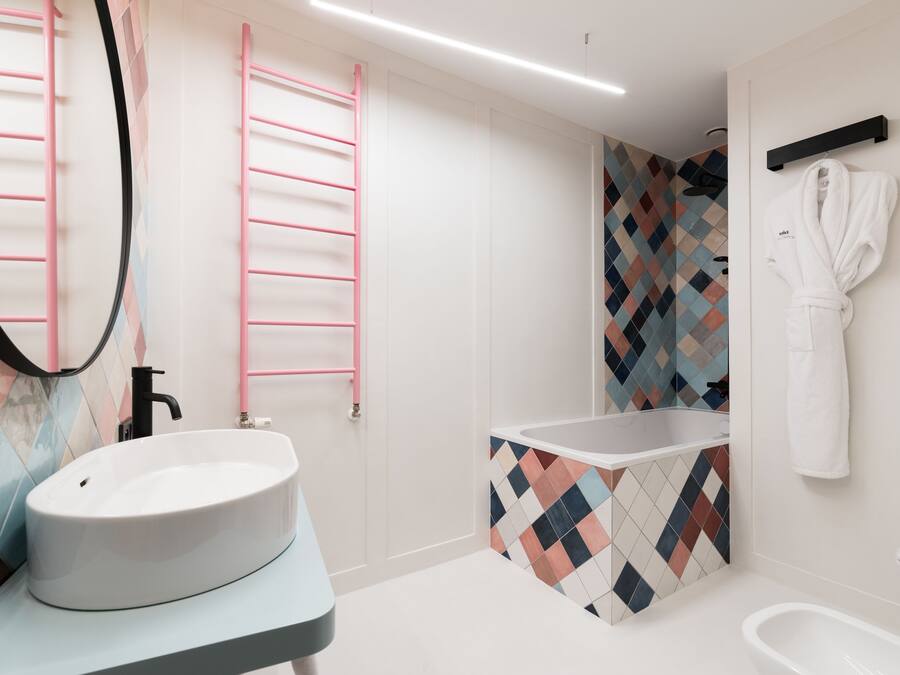A modern bathroom with a white sink, a freestanding bathtub, and a mirror with a pink towel rack.