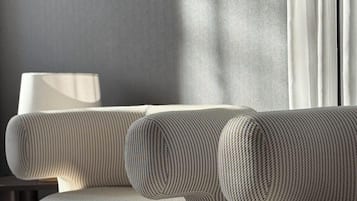 A modern living room with a grey sofa, a floor lamp, and a window with curtains.