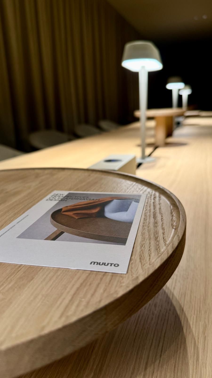 A wooden table with a Muuto brand placemat and a brochure.