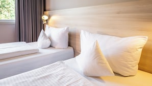 A hotel room with a wooden headboard, white bedding, and a nightlight on the wall. - Serways Hotel Nürnberg Feucht Ost (Schwarzenbruck)