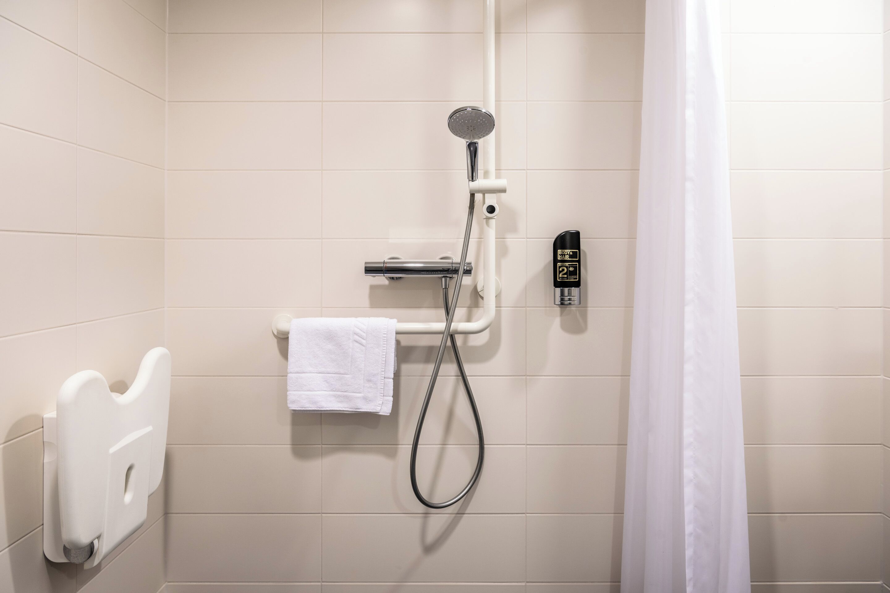 A shower area with a handheld showerhead, a towel rack, and a control panel.