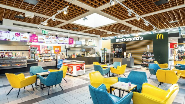 A modern fast-food restaurant with a McDonald's branding, featuring bright yellow and blue seating areas and a variety of food display counters. - Serways Hotel Nürnberg Feucht Ost (Schwarzenbruck)