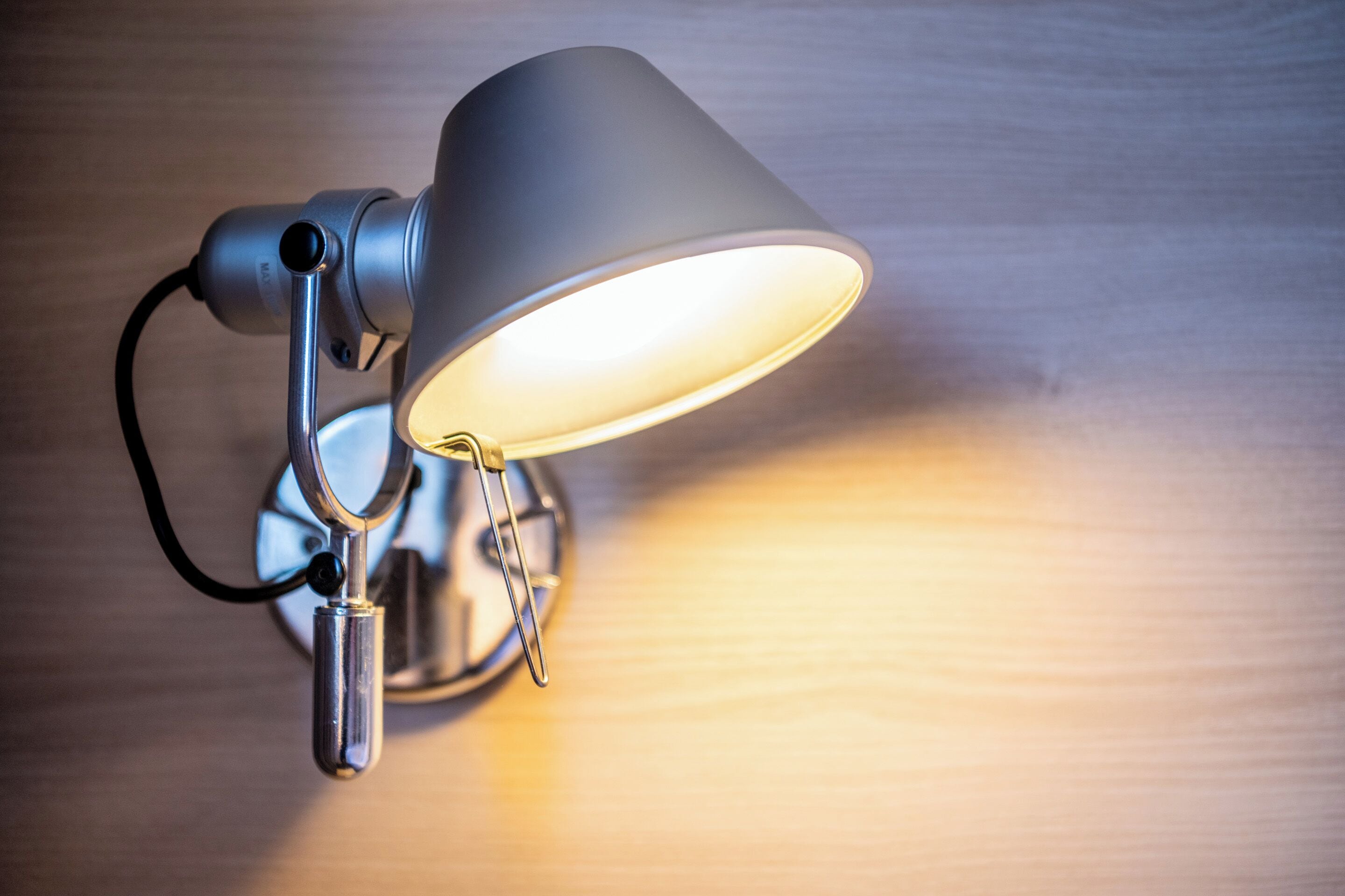 A wall-mounted lamp with a metallic finish and a flexible neck.
