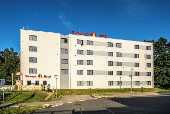 Un hotel de varios pisos con fachada plana, numerosas ventanas y cielo despejado.