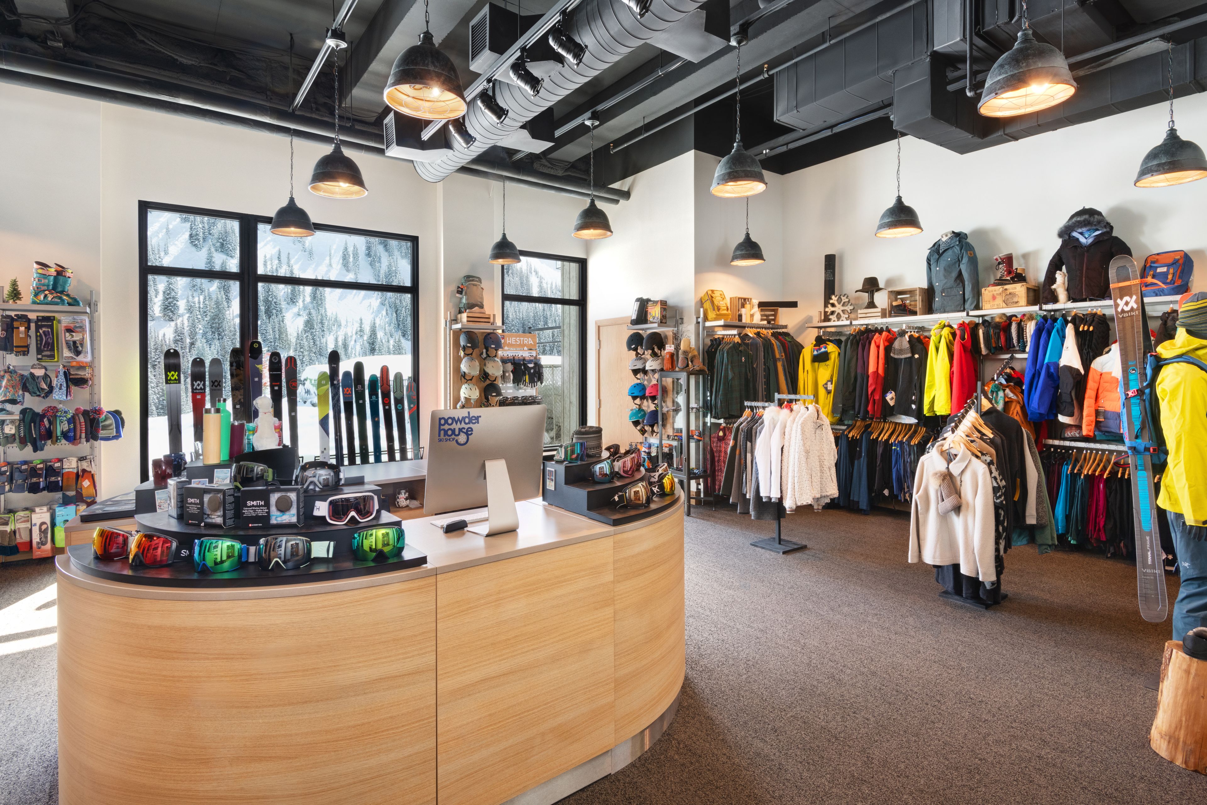 Tienda de equipo de esquí con mostrador de madera, porta esquíes y una amplia variedad de artículos de esquí.
