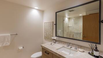 A modern bathroom with a large mirror, two sinks, a toilet, and a towel rack.