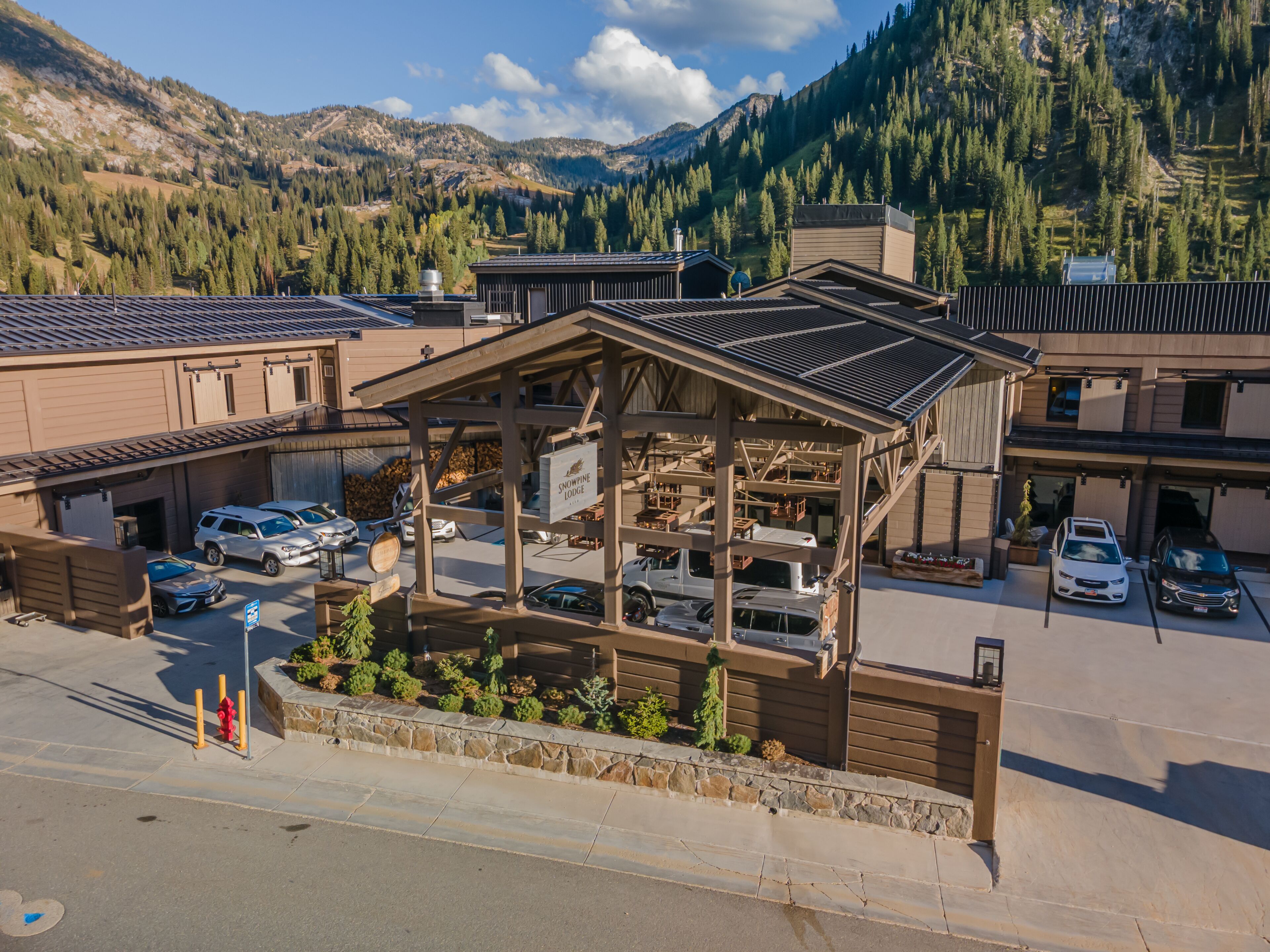 Un chalet doté d’un espace de stationnement couvert, de plusieurs véhicules et surplombant un paysage montagneux.