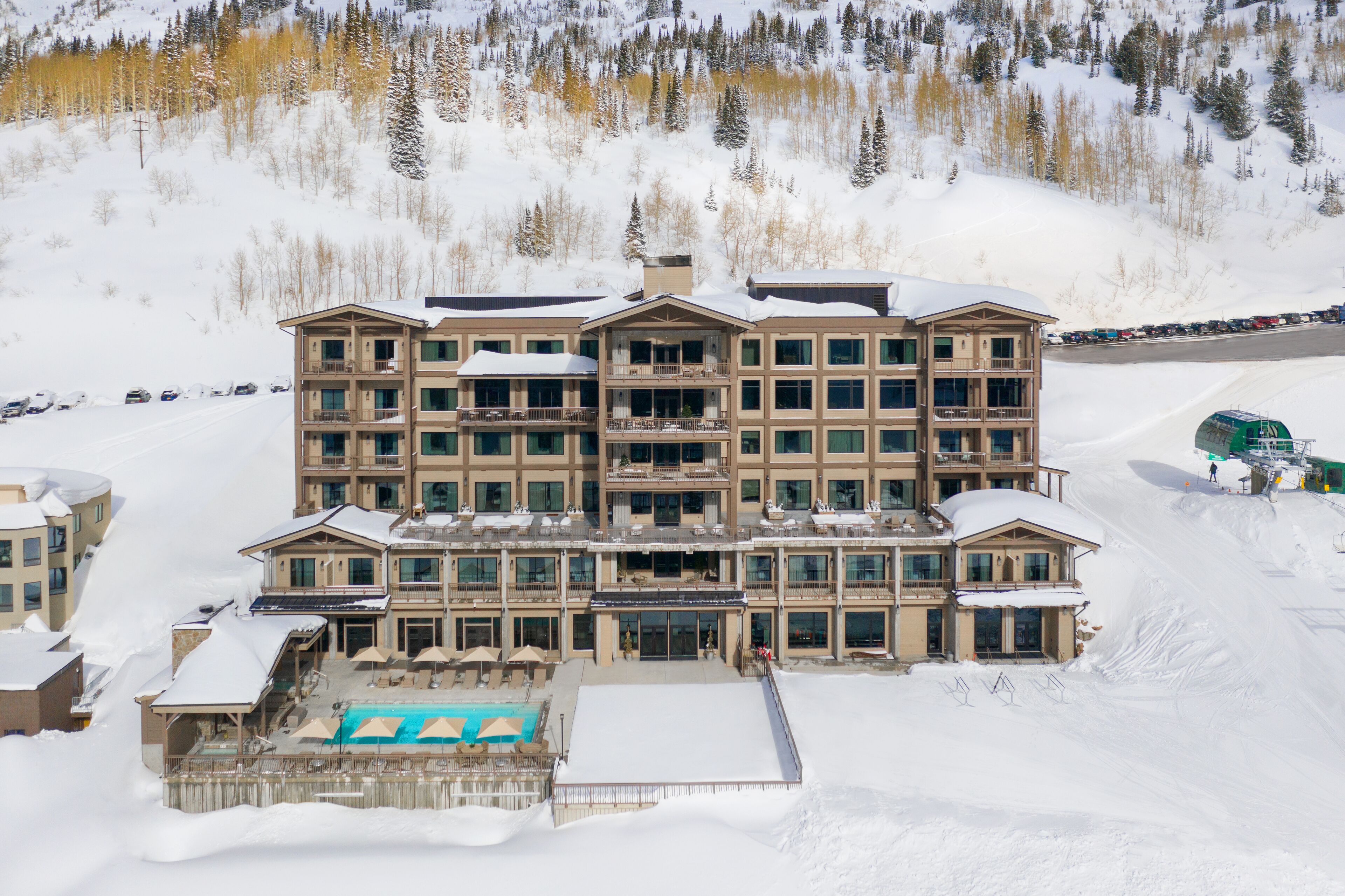 A multi-story hotel with a pool area and ski slope access.