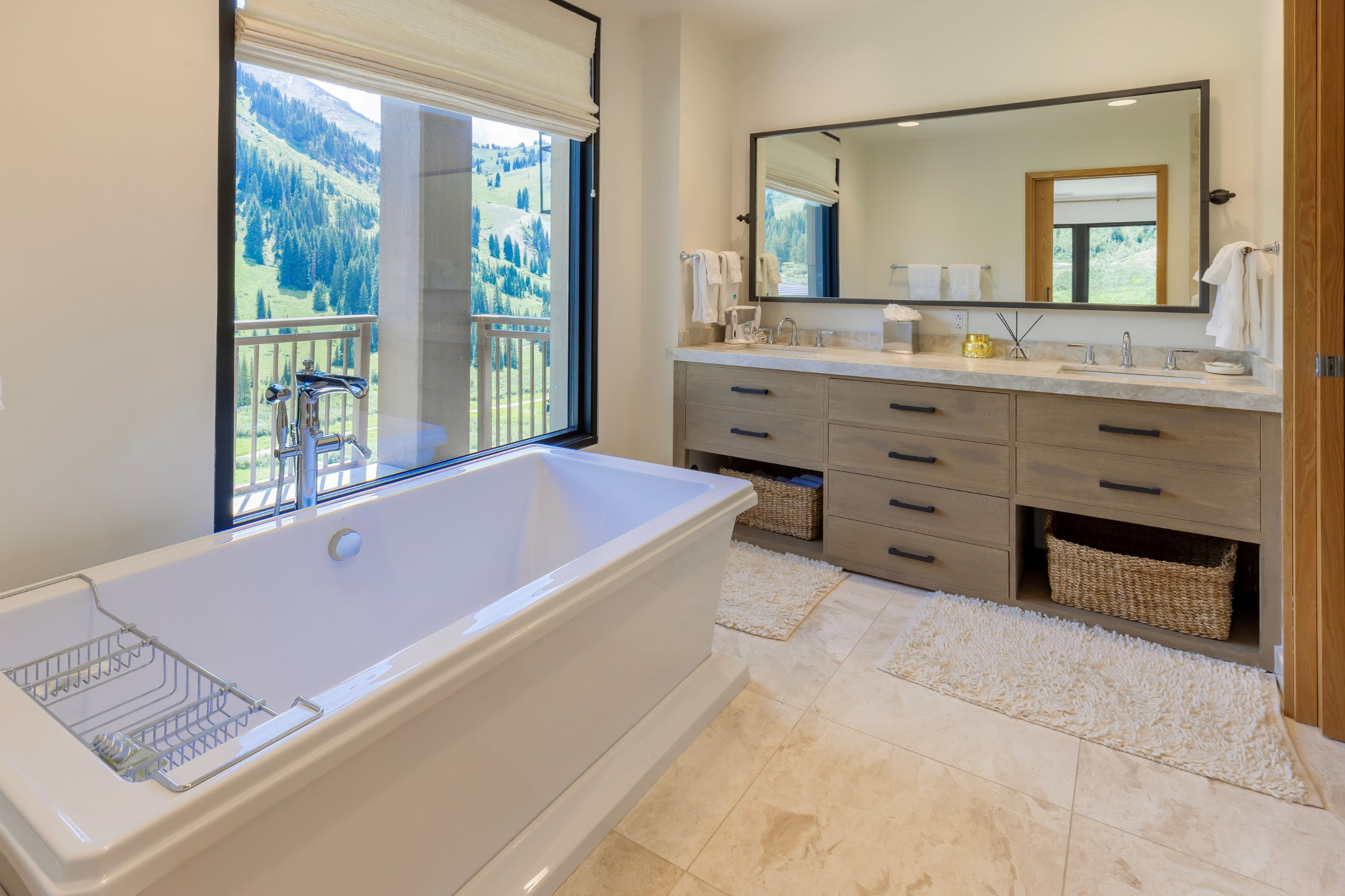 A modern bathroom with a large bathtub, a double sink vanity, and a large mirror.