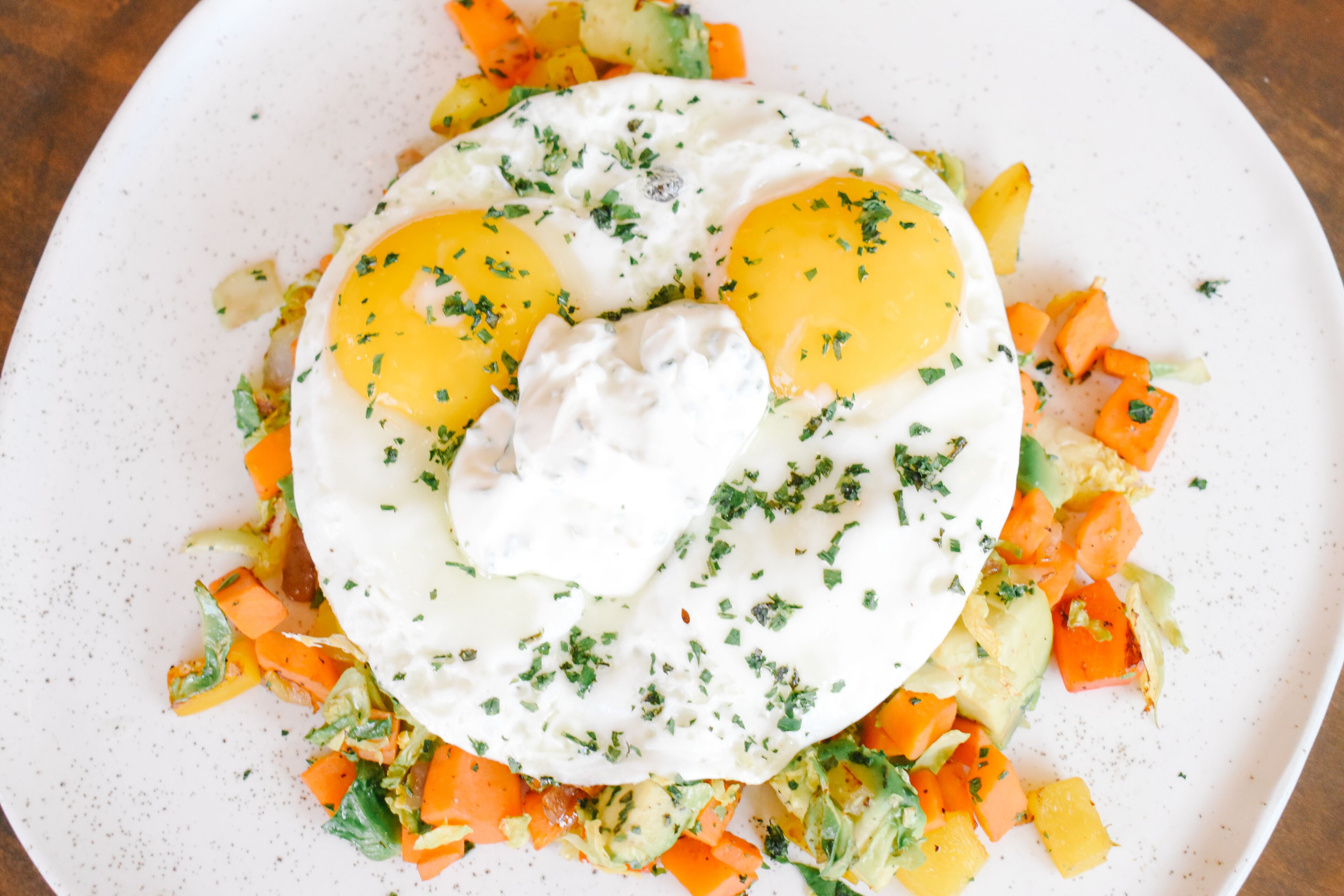 A plate of food with eggs, vegetables, and a creamy sauce.