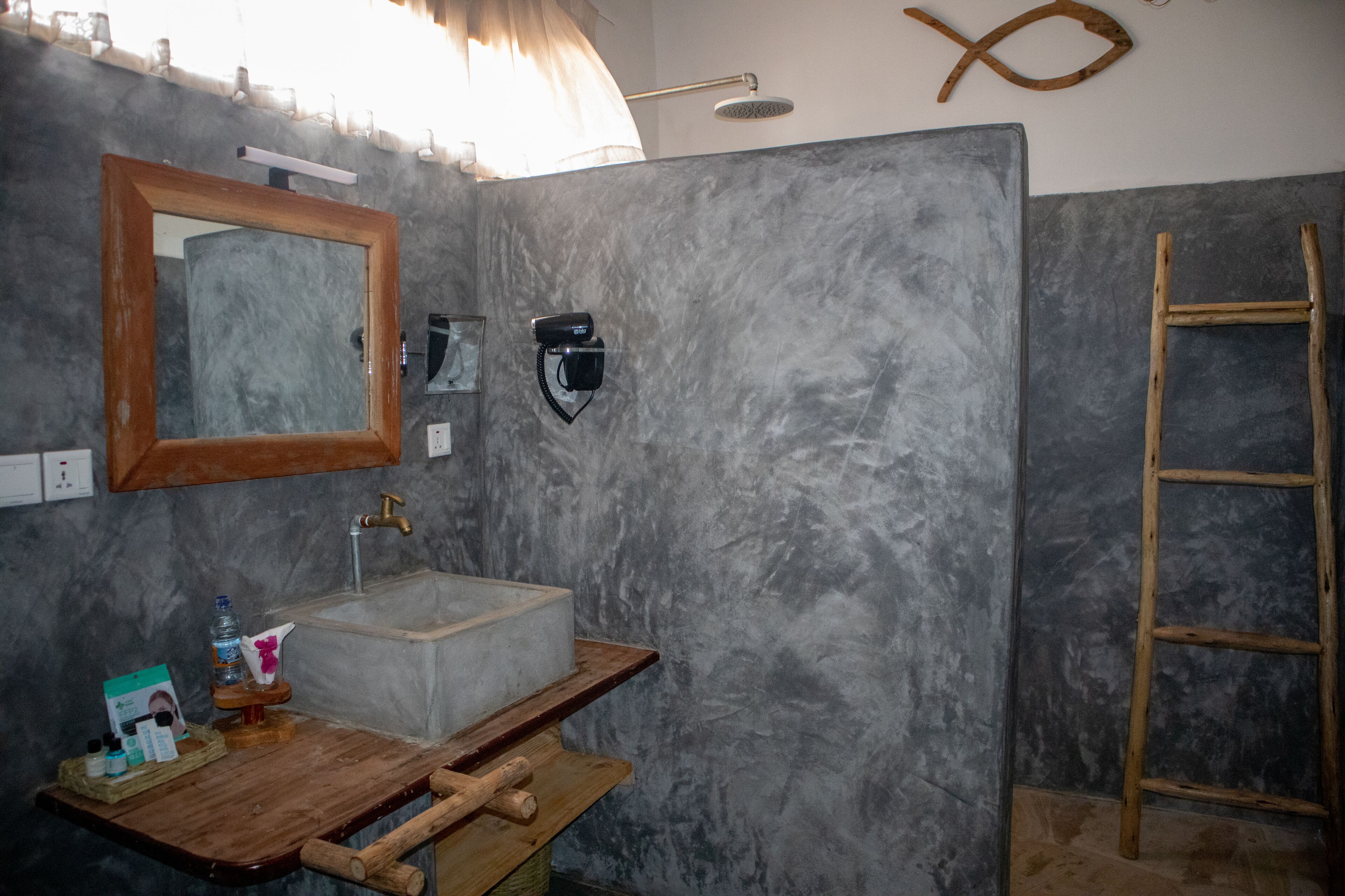 A bathroom with a marble sink, wooden vanity, a mirror, a towel rack, and a wooden ladder.
