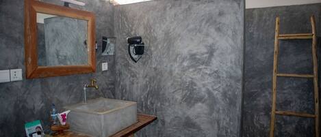 A bathroom with a marble sink, wooden vanity, a mirror, a towel rack, and a wooden ladder.