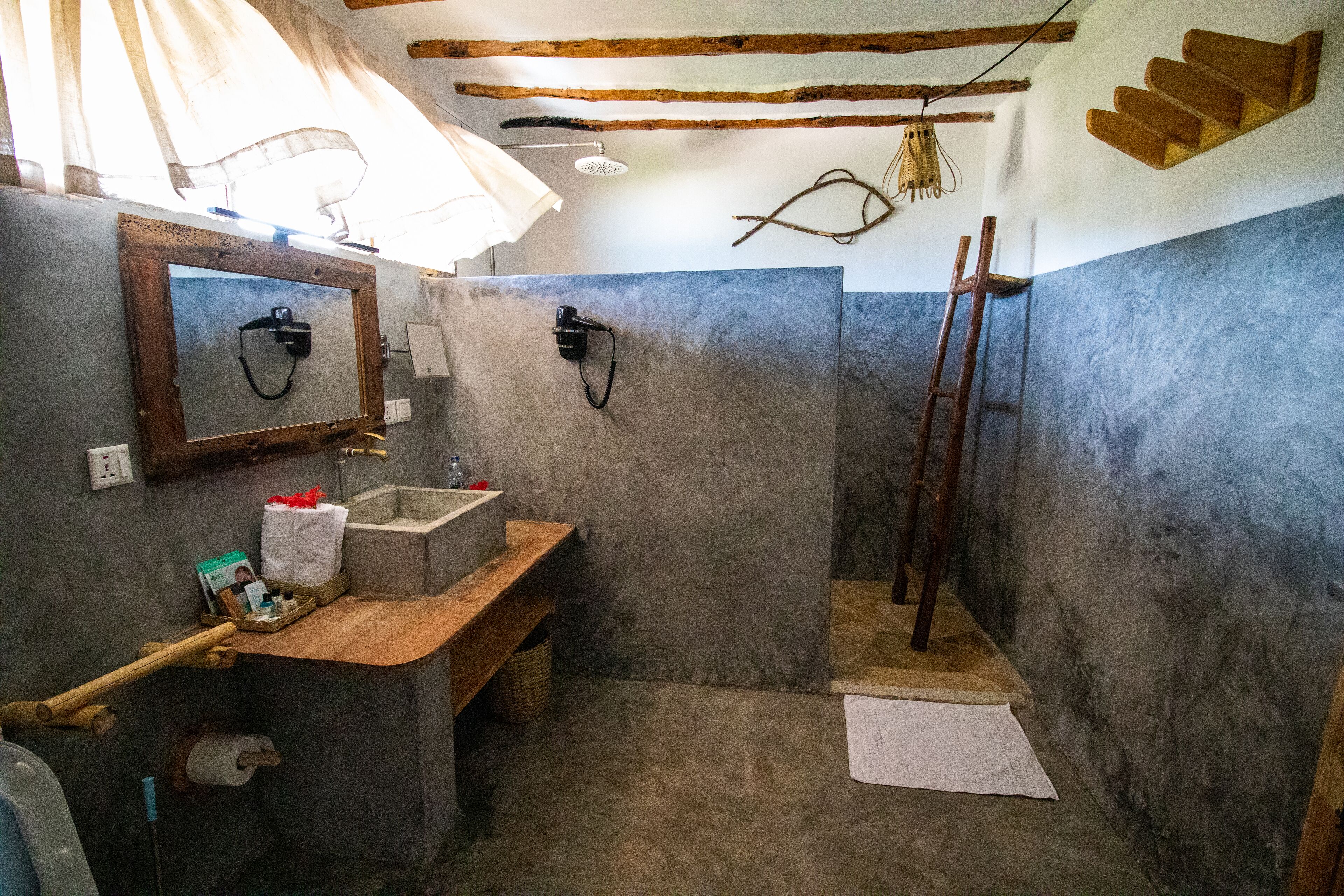 Ein rustikales Badezimmer mit einer Holzbank, einem Waschbecken und einer Dusche.