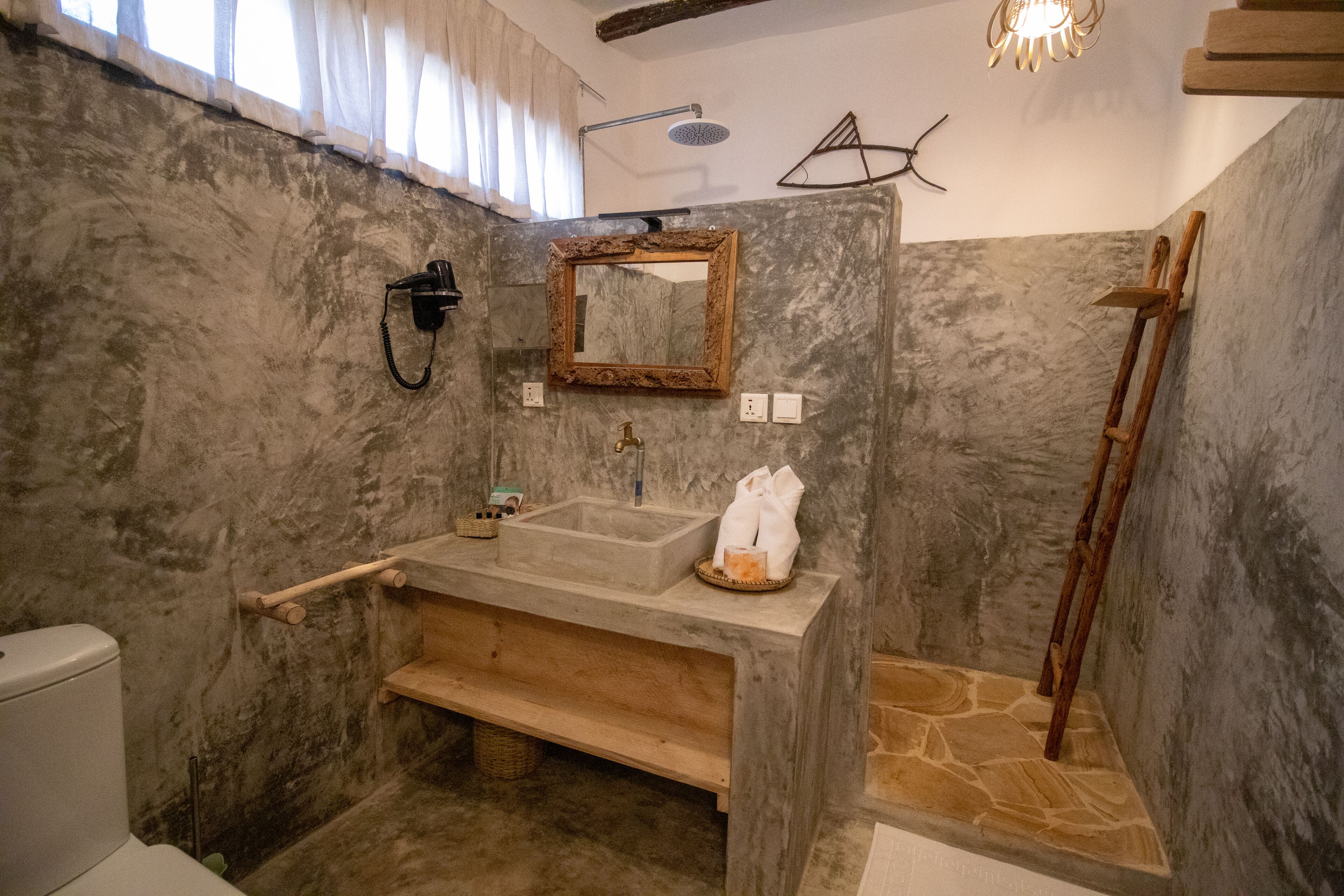 Ein Badezimmer mit einem Betonwaschbecken, Ablage aus Holz und einem Spiegel.