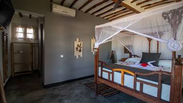 Un dormitorio con una cama de madera con dosel, un ventilador de techo y una ventana pequeña.