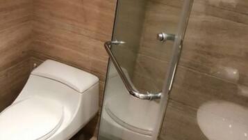 A bathroom with a glass shower enclosure, a toilet, and a sink.