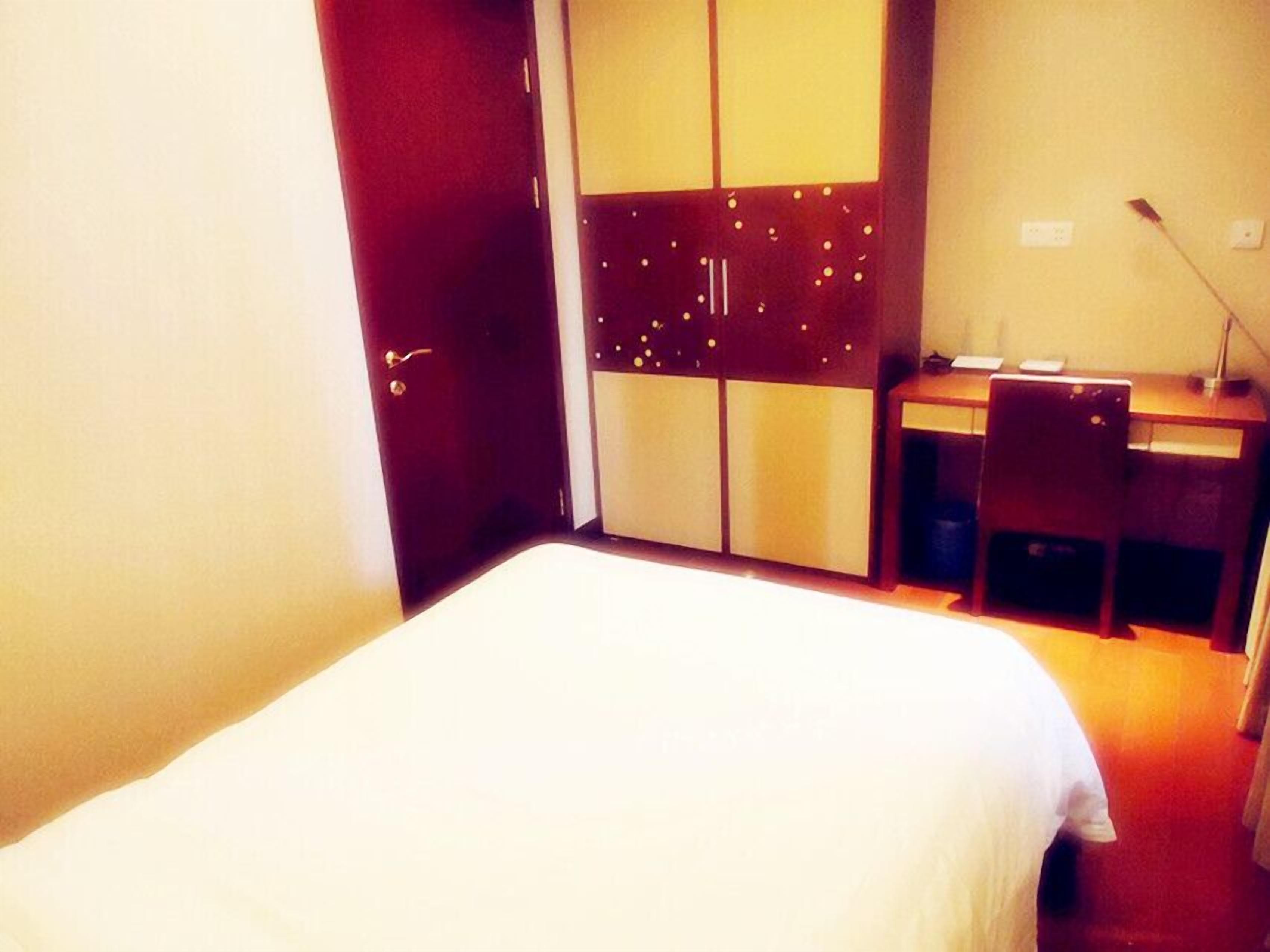 A hotel room with a bed, a desk, and a wardrobe.