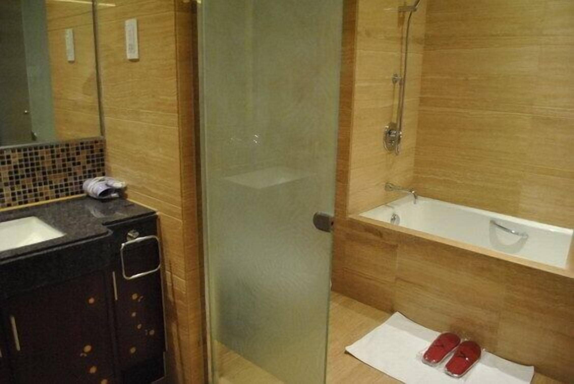 A bathroom with a glass shower door, a sink with a mirror, and a towel rack.