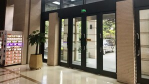 Entrada de hotel con puerta de vidrio, una máquina expendedora y una planta en maceta.