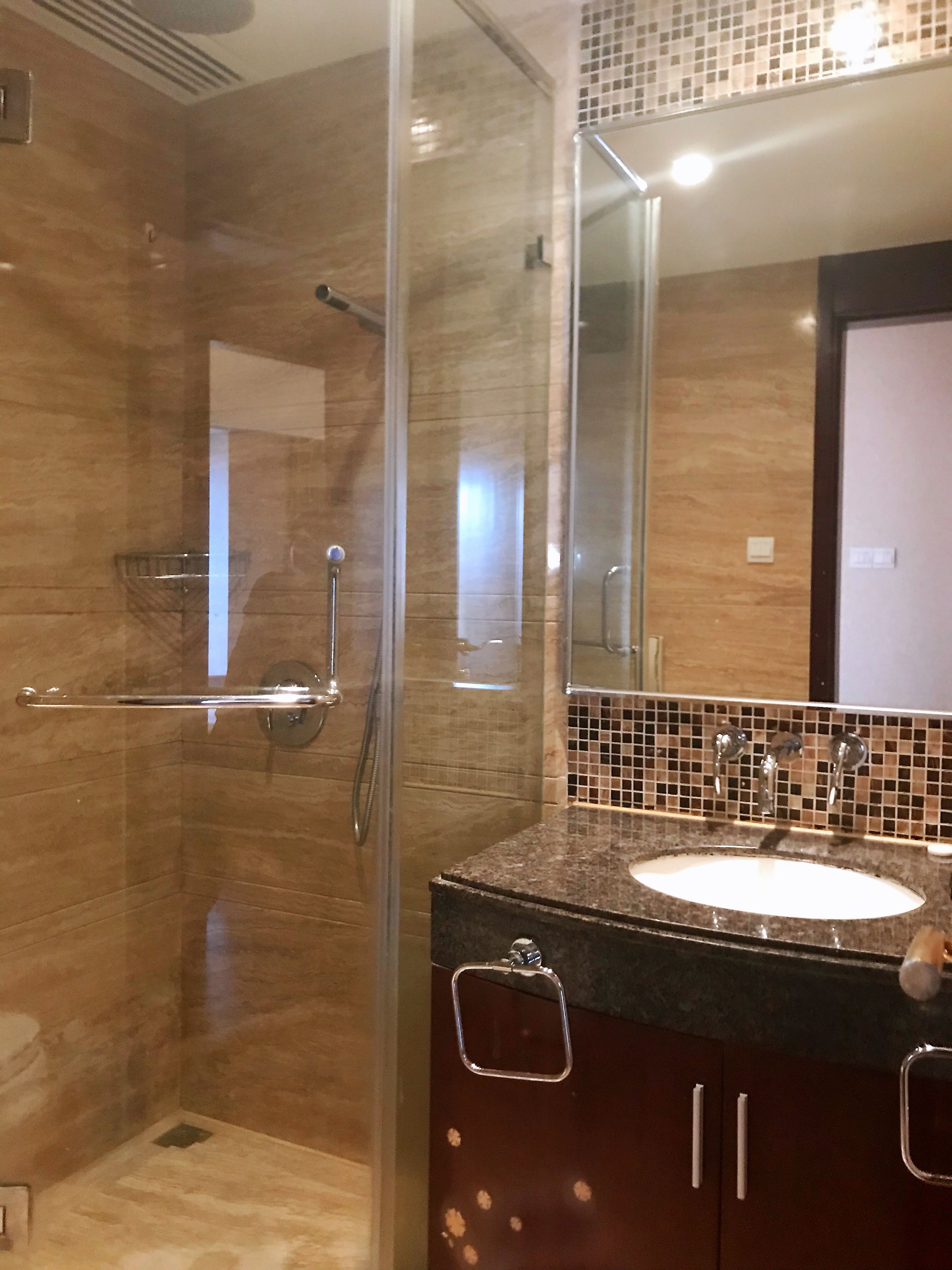 A bathroom with a glass-enclosed shower, a sink with a mirror above it, and a tiled backsplash.