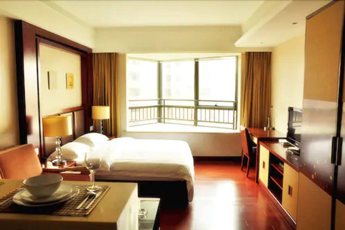 Une chambre d’hôtel comprenant un lit, un bureau, une table à manger avec un saladier et un verre à vin, une télévision et un balcon avec une balustrade.