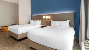 Una habitación de hotel con dos camas, una mesita de noche y un escritorio.